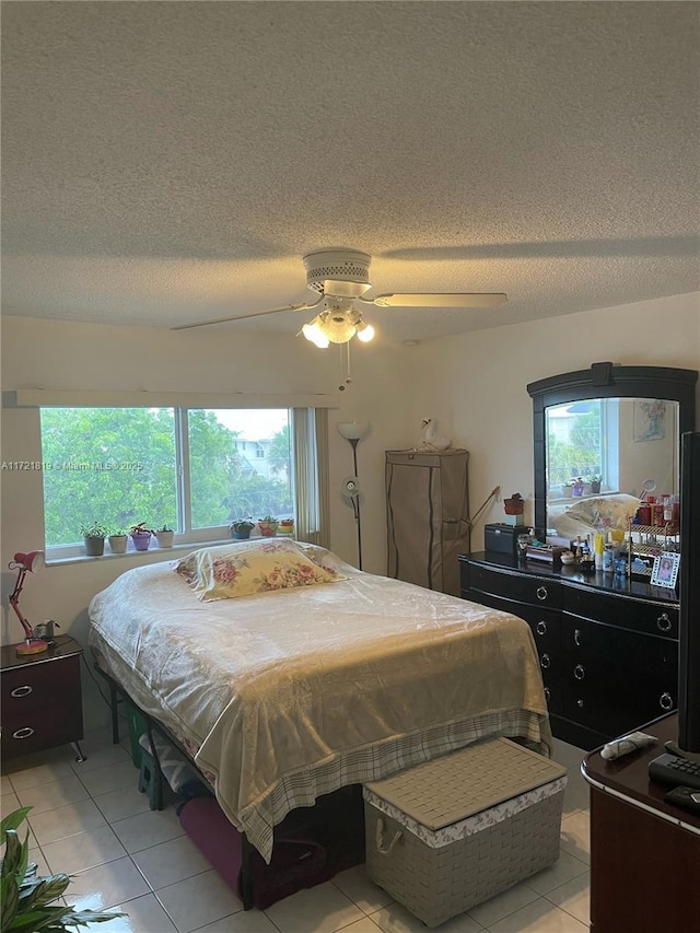 bedroom featuring ceiling fan, pool table, a textured ceiling, and light tile patterned floors