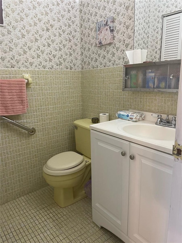 bathroom featuring toilet, tile patterned floors, tile walls, and vanity