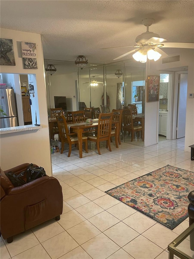 tiled dining area with a textured ceiling and ceiling fan