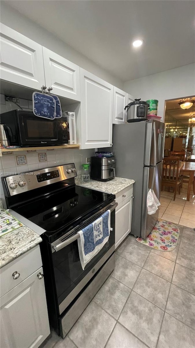 kitchen featuring light stone counters, white cabinets, appliances with stainless steel finishes, and light tile patterned flooring