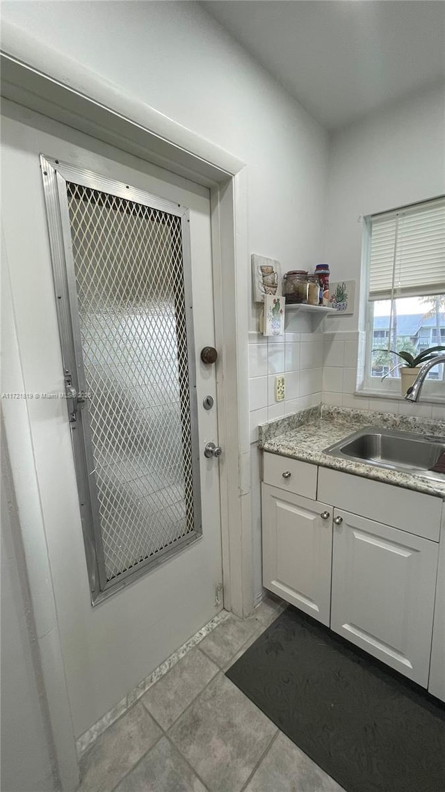 kitchen featuring white cabinets, light tile patterned floors, tasteful backsplash, and sink