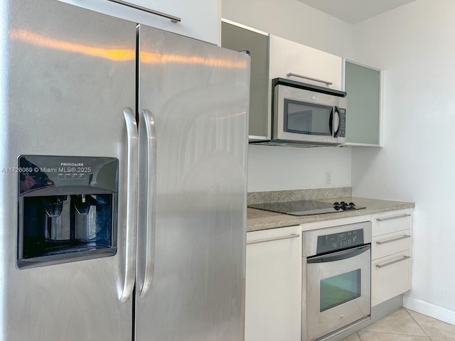 kitchen with stainless steel appliances, white cabinets, and light tile patterned floors