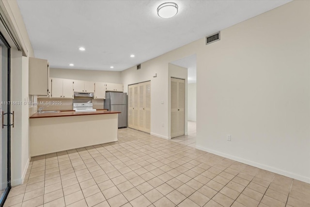 kitchen with white cabinetry, light tile patterned flooring, kitchen peninsula, white range with electric stovetop, and stainless steel fridge