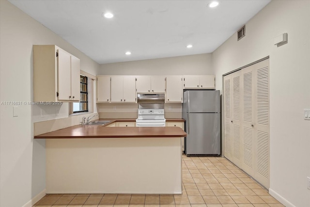 kitchen featuring white range with electric cooktop, stainless steel refrigerator, kitchen peninsula, white cabinets, and lofted ceiling