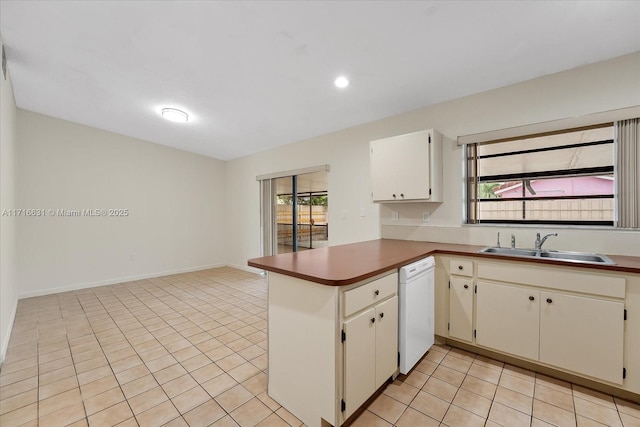 kitchen featuring dishwasher, kitchen peninsula, light tile patterned floors, white cabinets, and sink