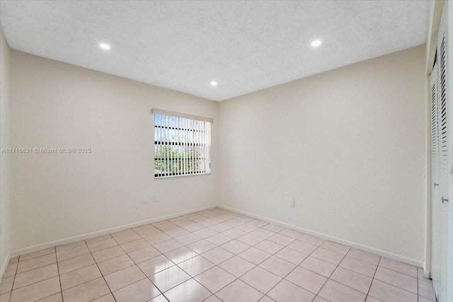 unfurnished room featuring a textured ceiling and light tile patterned floors