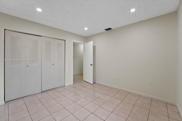 unfurnished bedroom featuring a textured ceiling, a closet, and light tile patterned floors