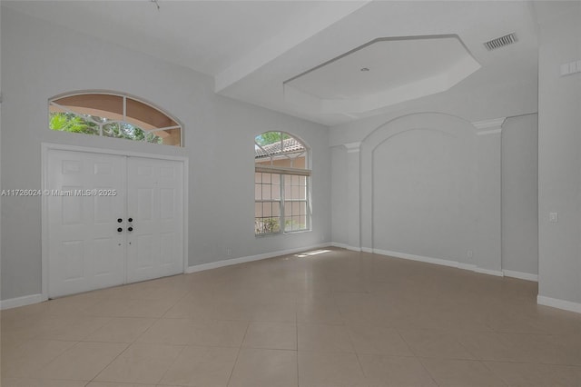 foyer entrance featuring a wealth of natural light, a tray ceiling, and light tile patterned flooring