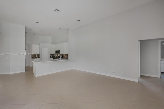 unfurnished living room featuring a towering ceiling and light tile patterned flooring