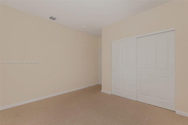 unfurnished bedroom with a closet and light colored carpet