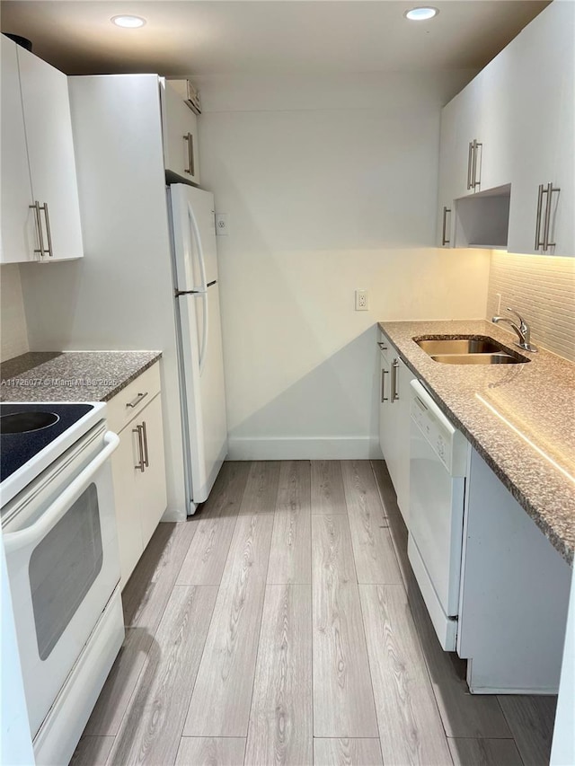 kitchen with sink, white appliances, white cabinets, and light hardwood / wood-style flooring