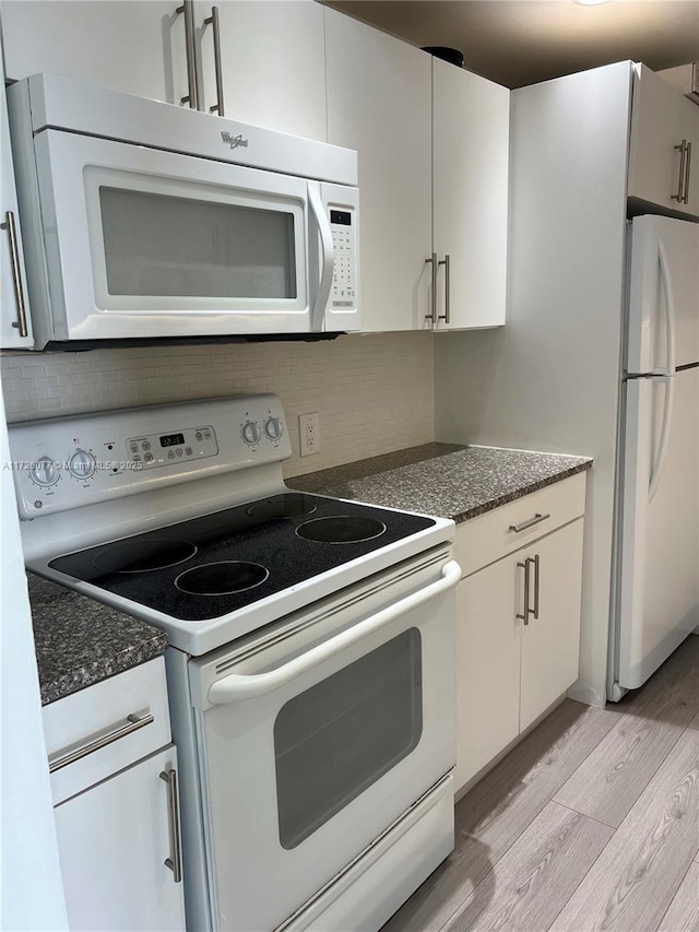 kitchen with decorative backsplash, white appliances, light wood-type flooring, dark stone counters, and white cabinets