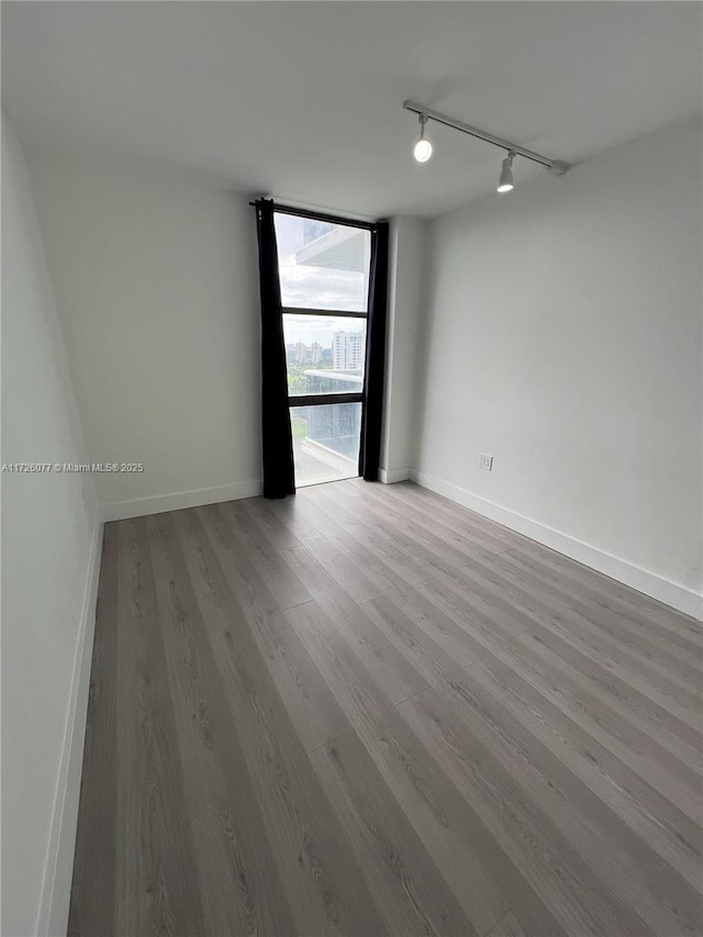 unfurnished room with rail lighting, light hardwood / wood-style floors, and expansive windows