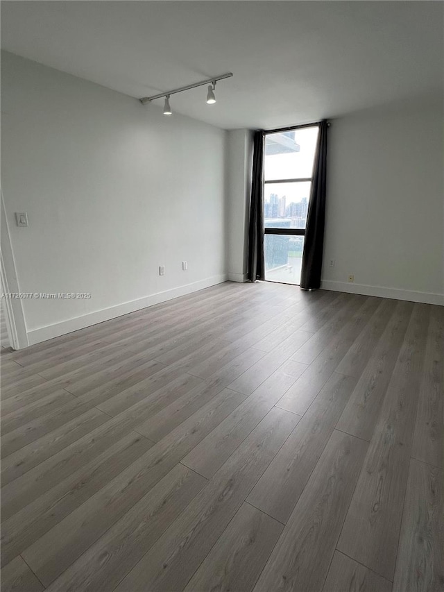 unfurnished room featuring hardwood / wood-style flooring, track lighting, and floor to ceiling windows