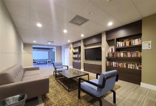 living room featuring carpet floors, a drop ceiling, and built in features