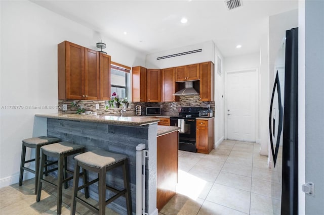 18253 SW 152nd Pl, Miami, FL 33187 - kitchen featuring kitchen peninsula, wall chimney exhaust hood, black appliances, and a kitchen bar