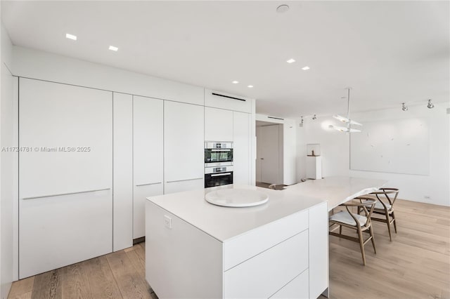 kitchen with a kitchen island, white cabinets, and light hardwood / wood-style floors