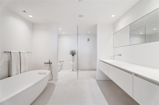 bathroom with toilet, a tub, a bidet, and vanity