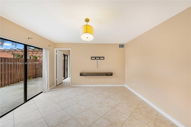 tiled empty room with a textured ceiling