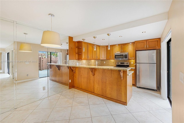 kitchen with hanging light fixtures, light tile patterned floors, stainless steel appliances, and a breakfast bar area