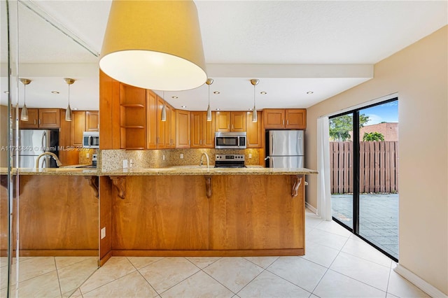 kitchen with stainless steel appliances, tasteful backsplash, light tile patterned flooring, hanging light fixtures, and light stone counters