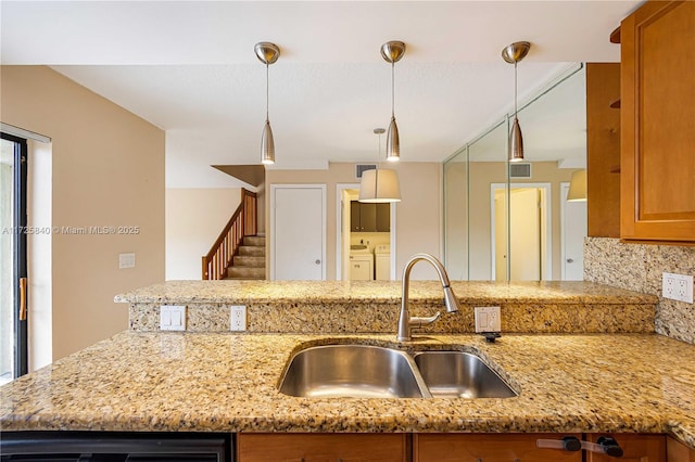 kitchen featuring light stone countertops, washer and dryer, tasteful backsplash, and sink