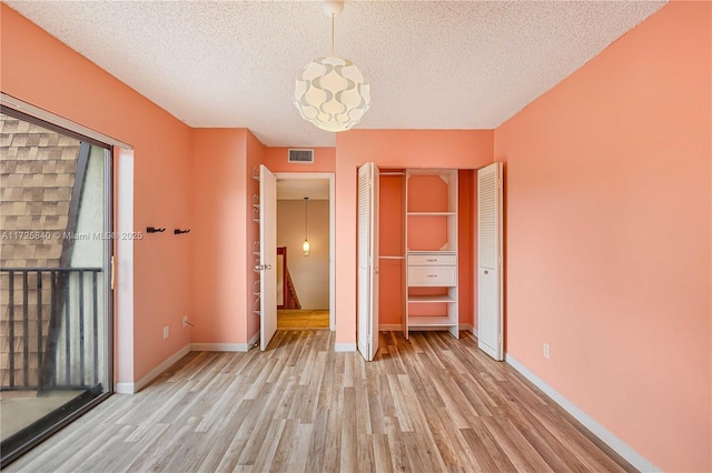 unfurnished bedroom featuring a textured ceiling, a closet, and light hardwood / wood-style flooring