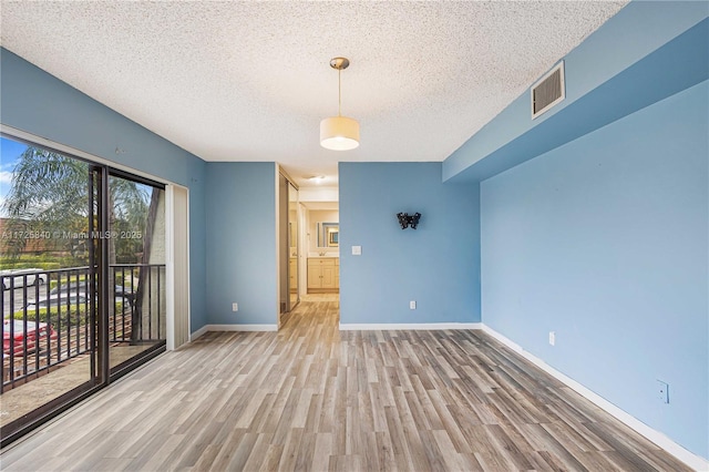 unfurnished room with a textured ceiling and light hardwood / wood-style floors