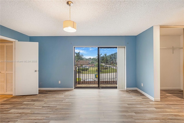 unfurnished bedroom with access to exterior, a textured ceiling, a closet, and light hardwood / wood-style flooring