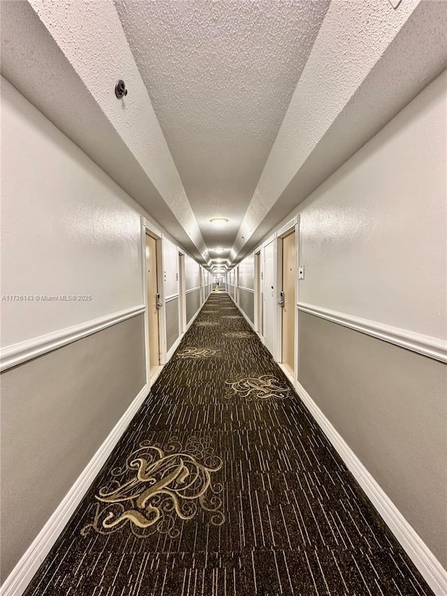 corridor featuring a textured ceiling and carpet flooring