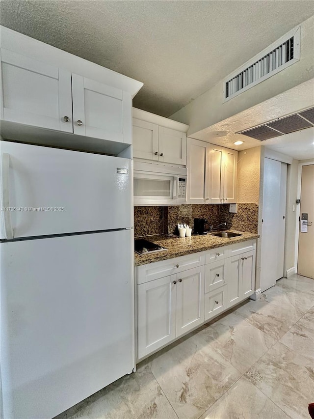 kitchen with white cabinetry, sink, dark stone counters, and white appliances