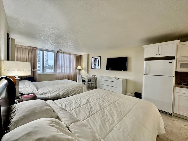 bedroom with a textured ceiling and white refrigerator