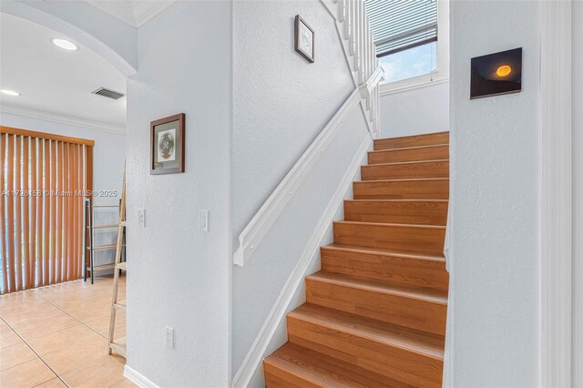 staircase with ornamental molding and tile patterned floors