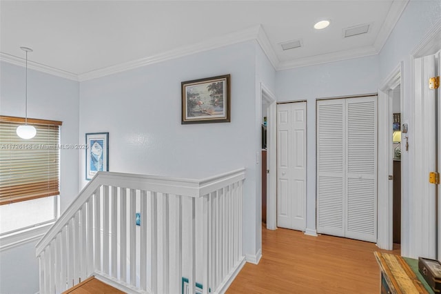 hallway with light wood-type flooring and crown molding