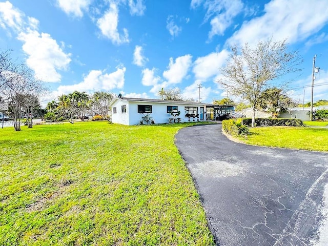 ranch-style house featuring aphalt driveway and a front lawn