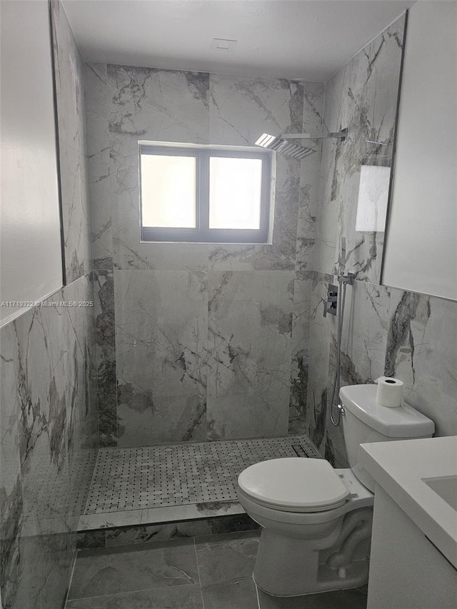 bathroom featuring tile walls, tiled shower, vanity, and toilet