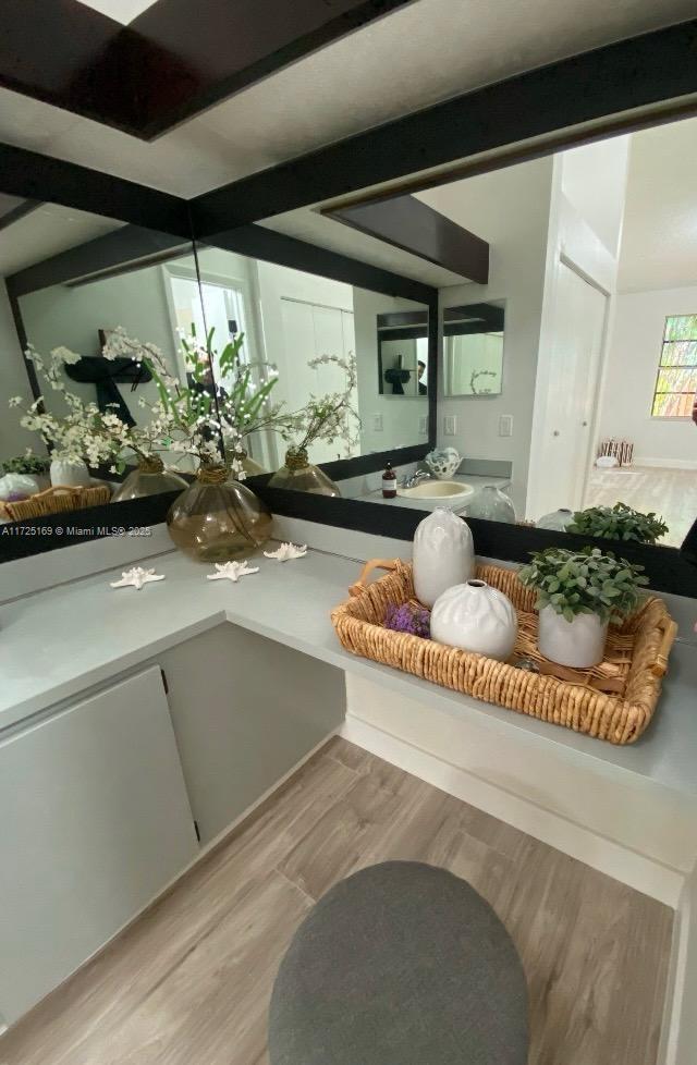 room details with sink, beamed ceiling, and hardwood / wood-style flooring