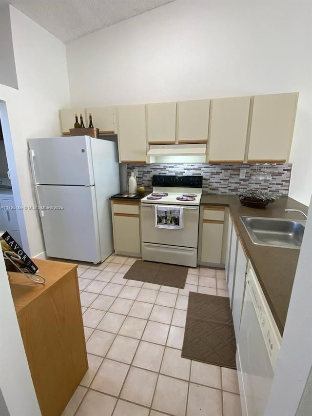 kitchen with white appliances, light tile patterned floors, a textured ceiling, cream cabinets, and sink