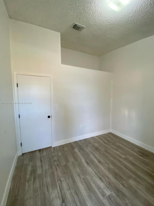 empty room featuring a textured ceiling and dark hardwood / wood-style floors