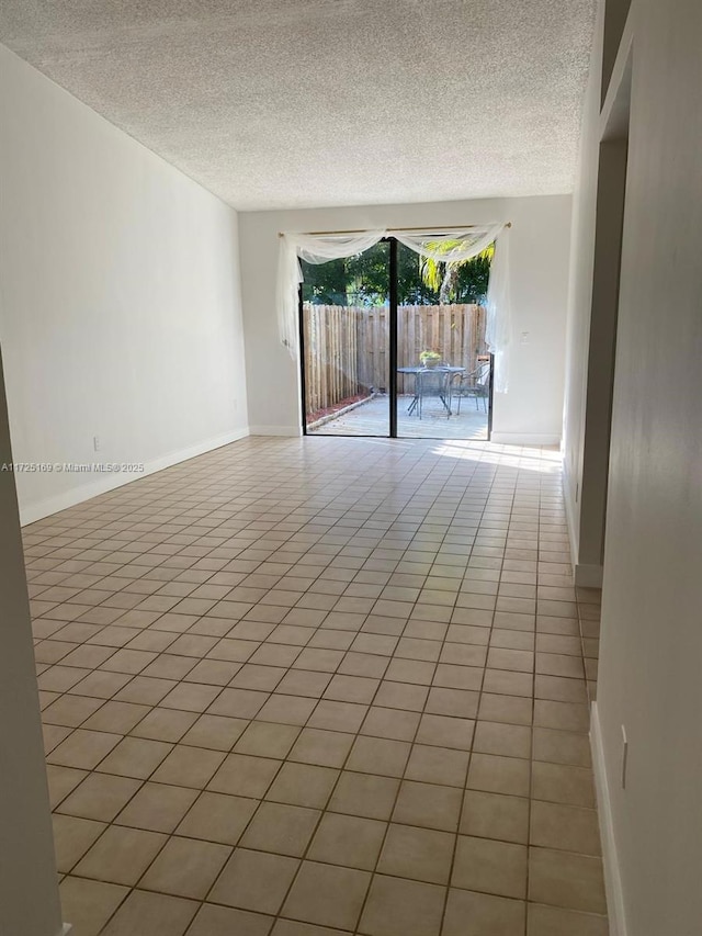 tiled empty room featuring a textured ceiling