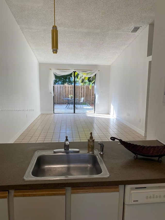 kitchen featuring white dishwasher, tile patterned flooring, a textured ceiling, and sink