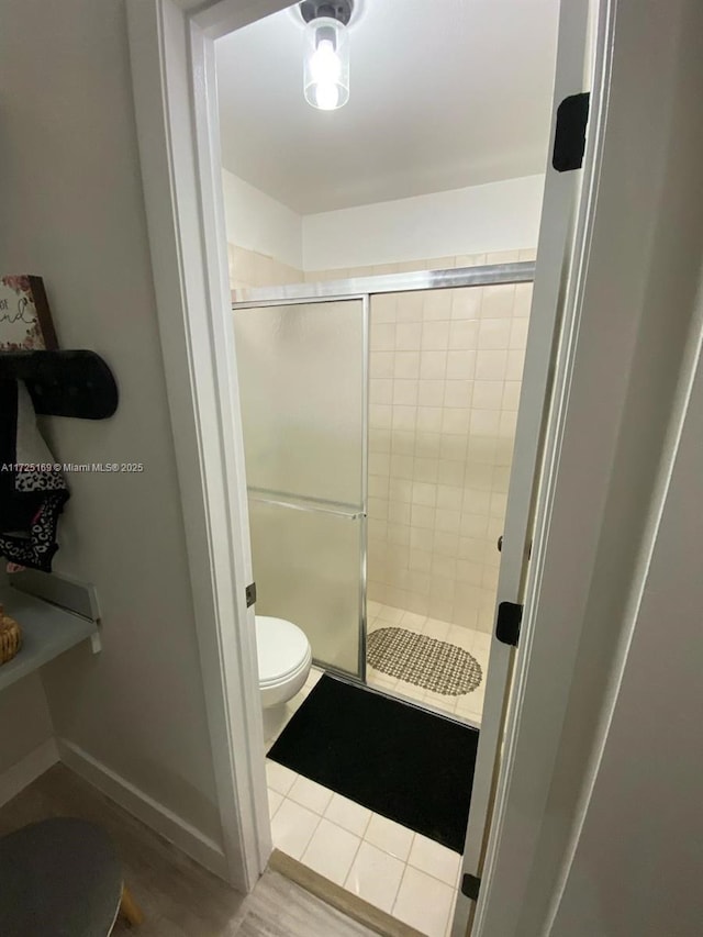 bathroom with a shower with door and toilet