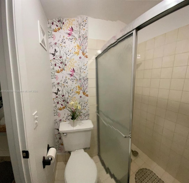 bathroom with toilet, a shower with door, and tile patterned floors