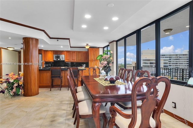 tiled dining area featuring sink and crown molding