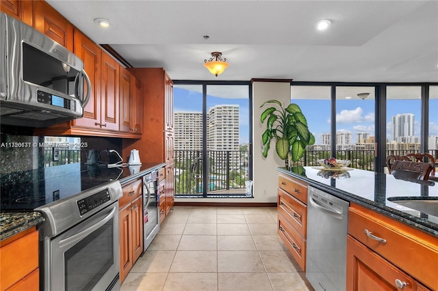 kitchen featuring stainless steel appliances, light tile patterned flooring, a wealth of natural light, and dark stone counters