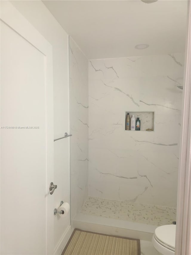 bathroom with toilet and a tile shower