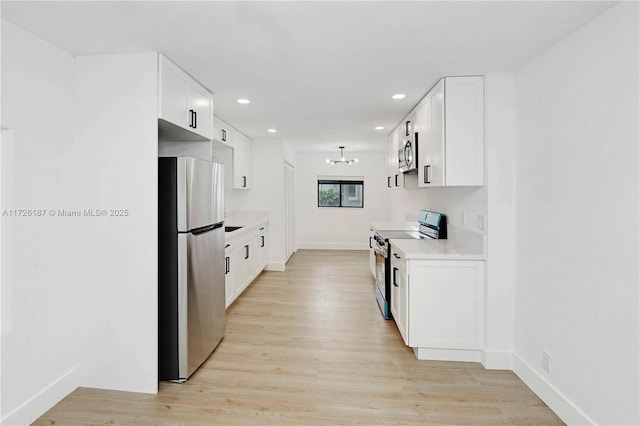 kitchen with light hardwood / wood-style floors, stainless steel appliances, white cabinetry, and an inviting chandelier