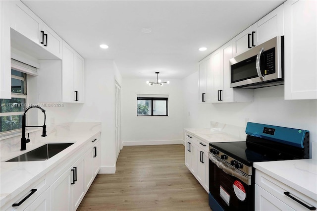 kitchen featuring sink, stainless steel appliances, a notable chandelier, and white cabinetry