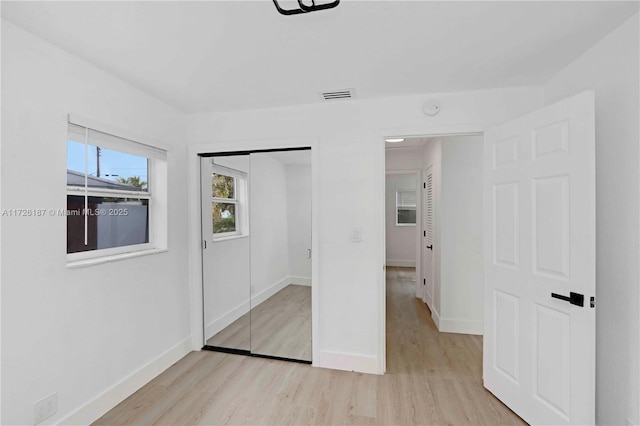 unfurnished bedroom with a closet and light wood-type flooring