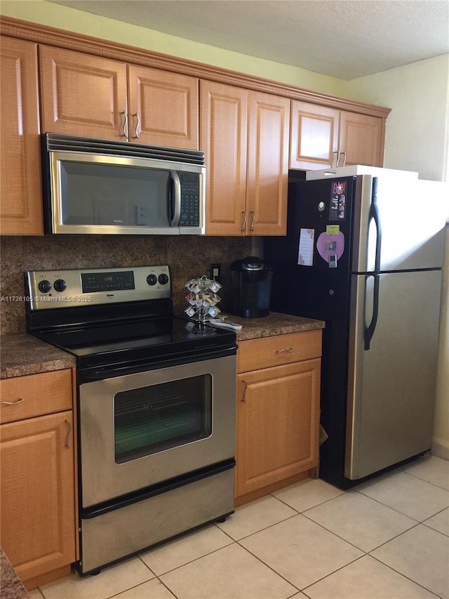 kitchen featuring stainless steel appliances, decorative backsplash, and light tile patterned floors